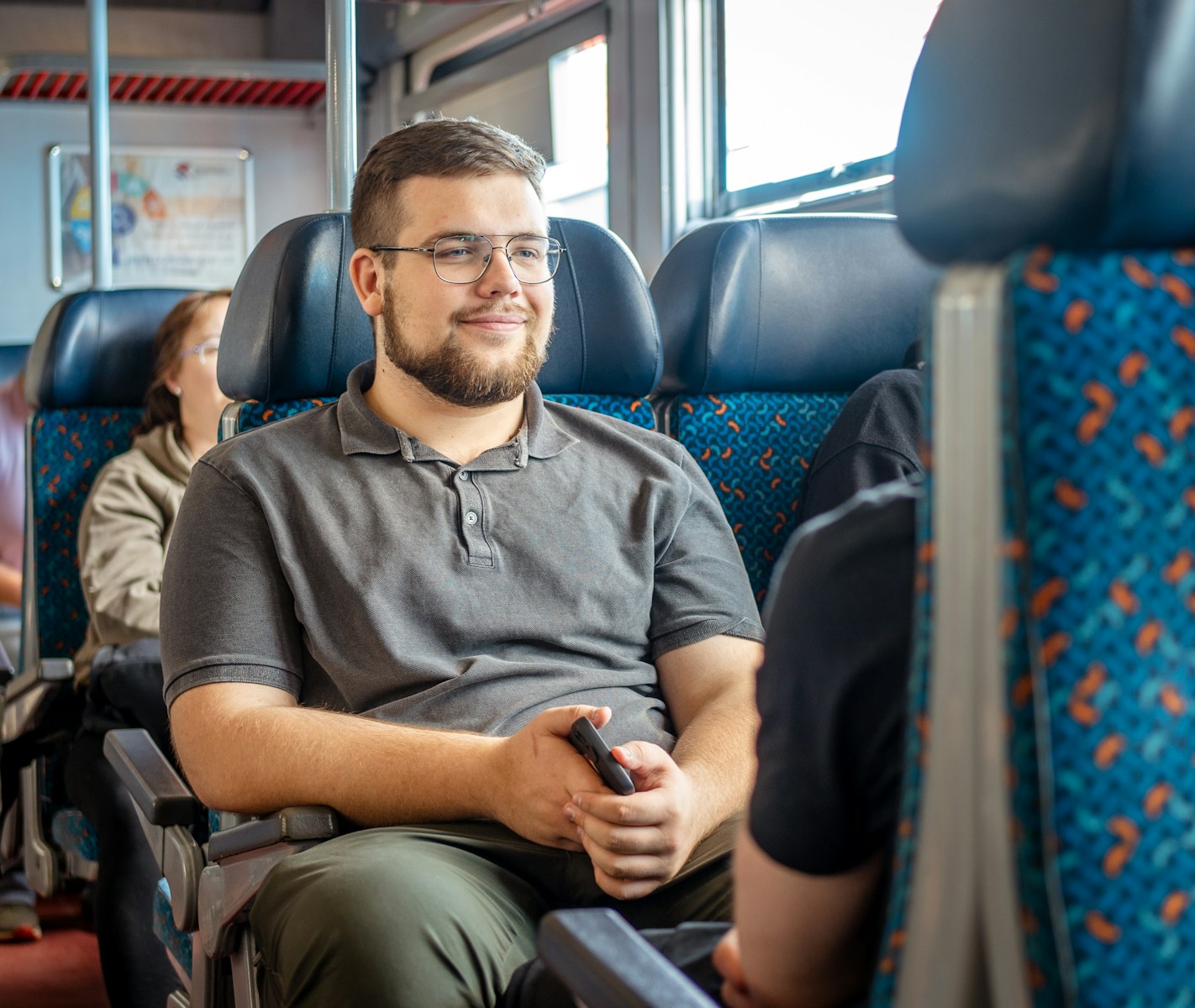 A man smiles while sitting on a train.