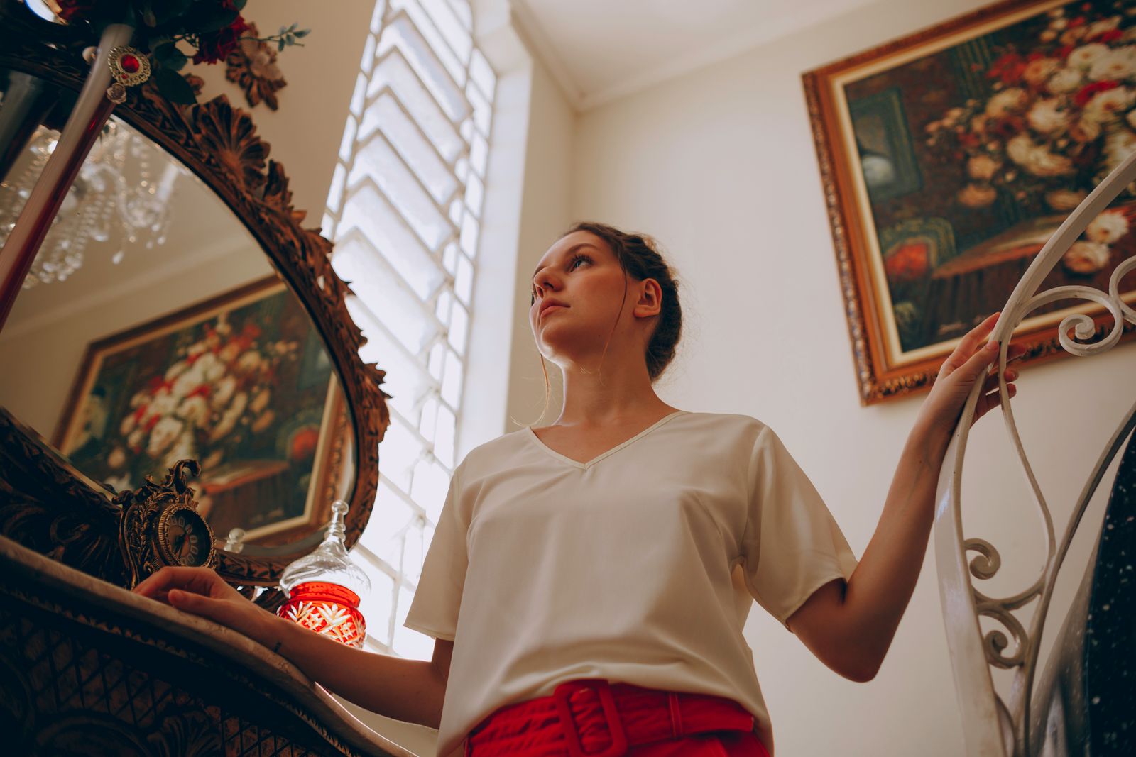 Elegant portrait of a woman posing near a mirror in a tastefully decorated interior.