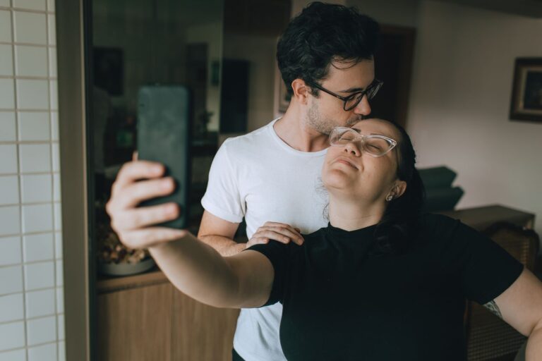 A loving couple capture a joyful selfie moment indoors, showcasing affection and happiness.
