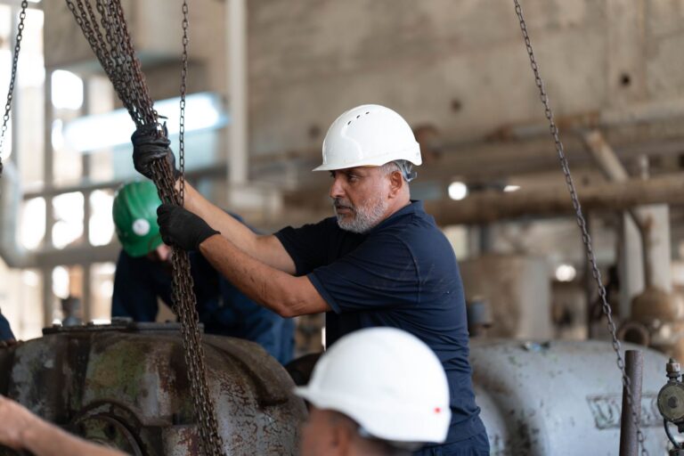 Workers with helmets operating chains in an industrial setting, Libya.