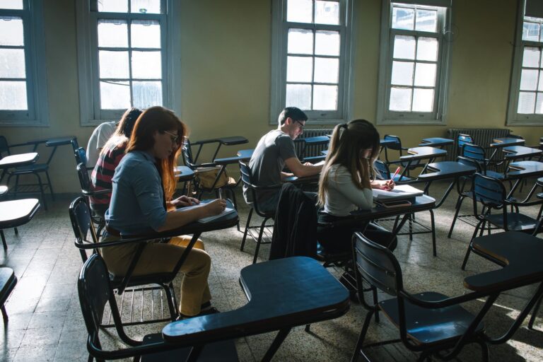A group of students focused on taking a test in a sunlit classroom setting.