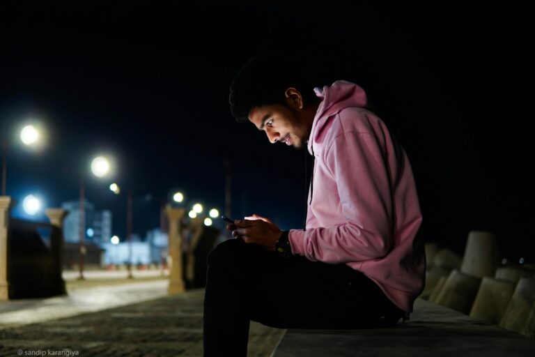 a man sitting on a bench looking at his cell phone