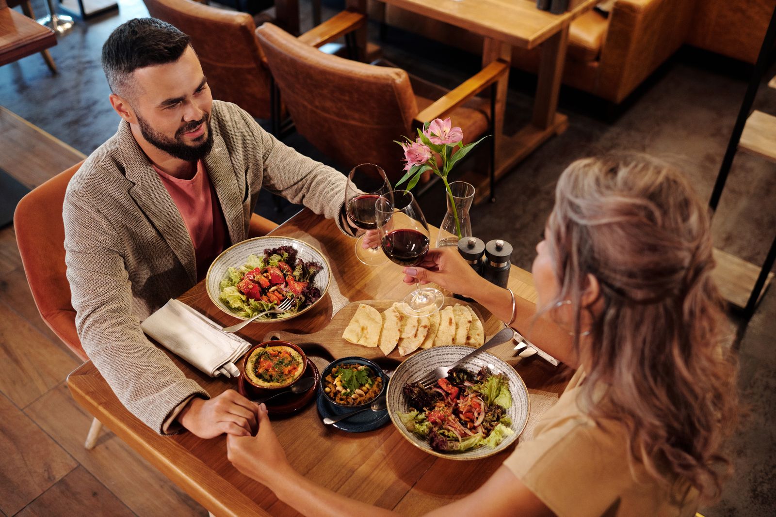Couple enjoying a romantic dinner with wine at a cozy restaurant table.