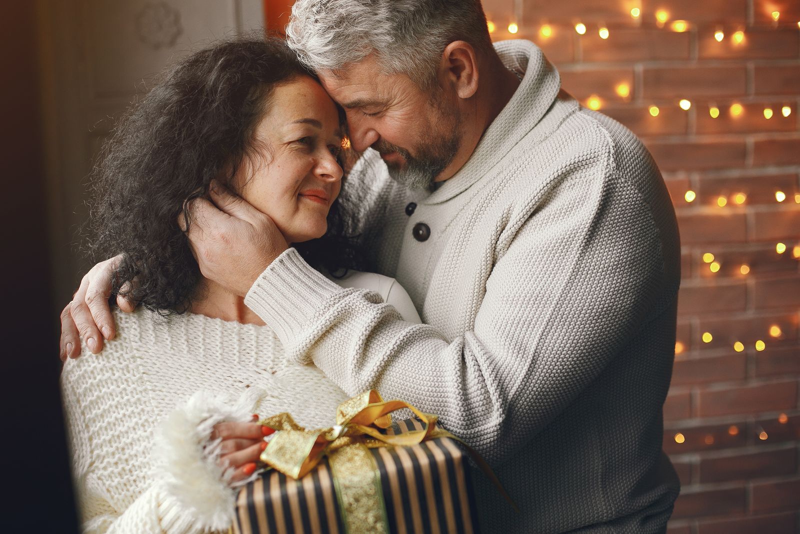 A loving couple exchanges a wrapped gift, symbolizing warmth and affection.