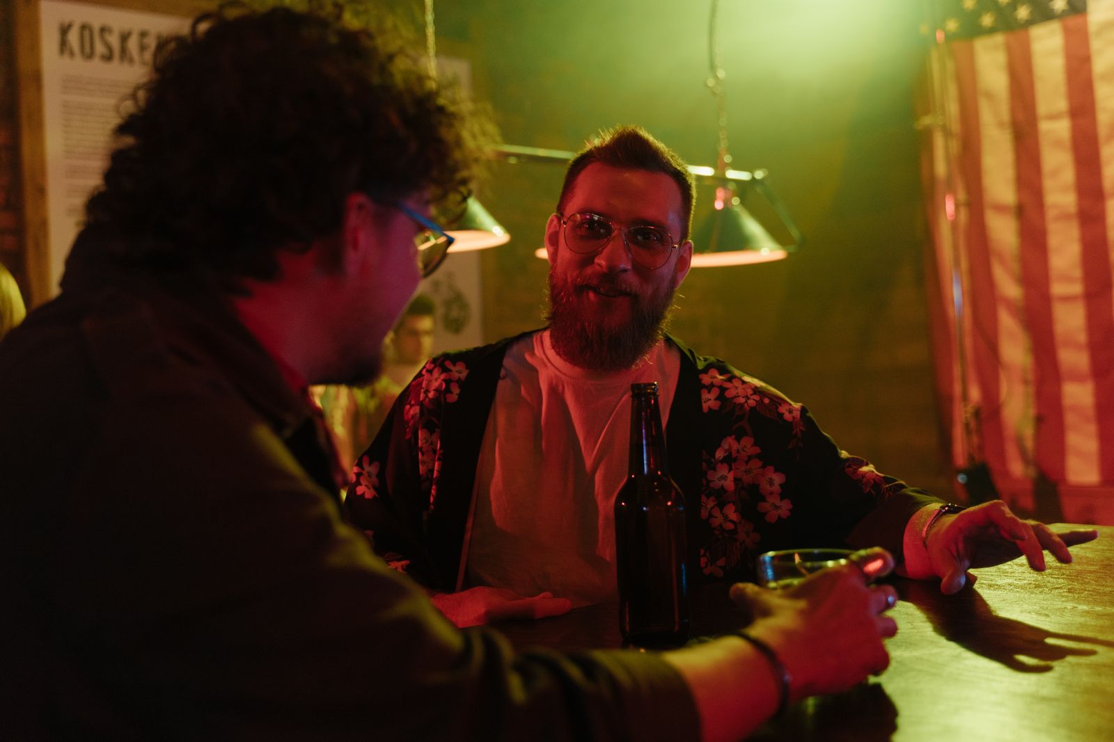 Two men enjoying a drink at a bar with relaxed atmosphere and soft lighting.
