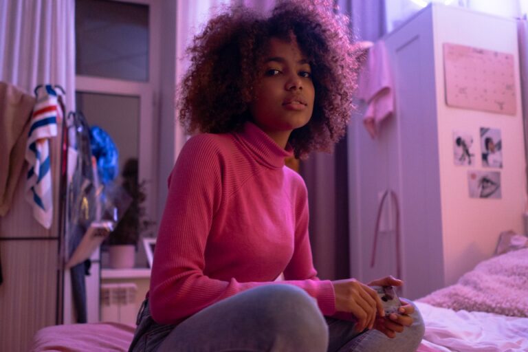Young woman lounging in a cozy bedroom with a playful pink ambiance.