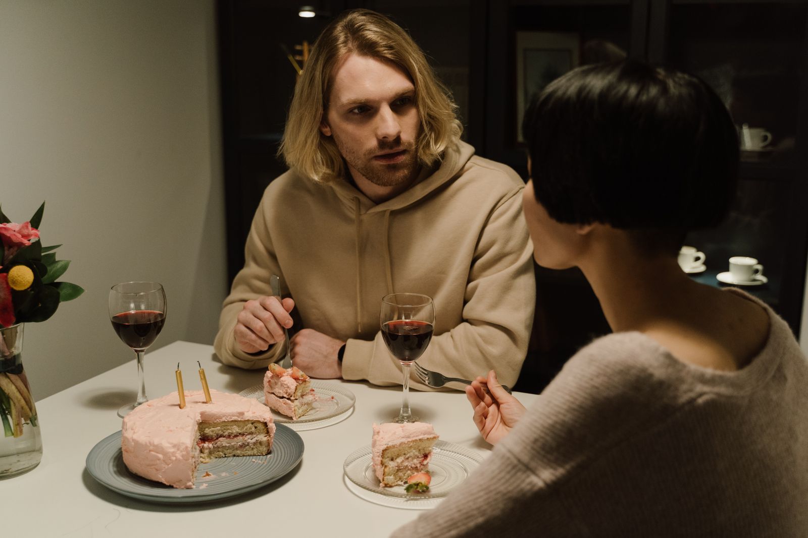 A couple shares a moment over cake and wine at home, creating a cozy atmosphere.