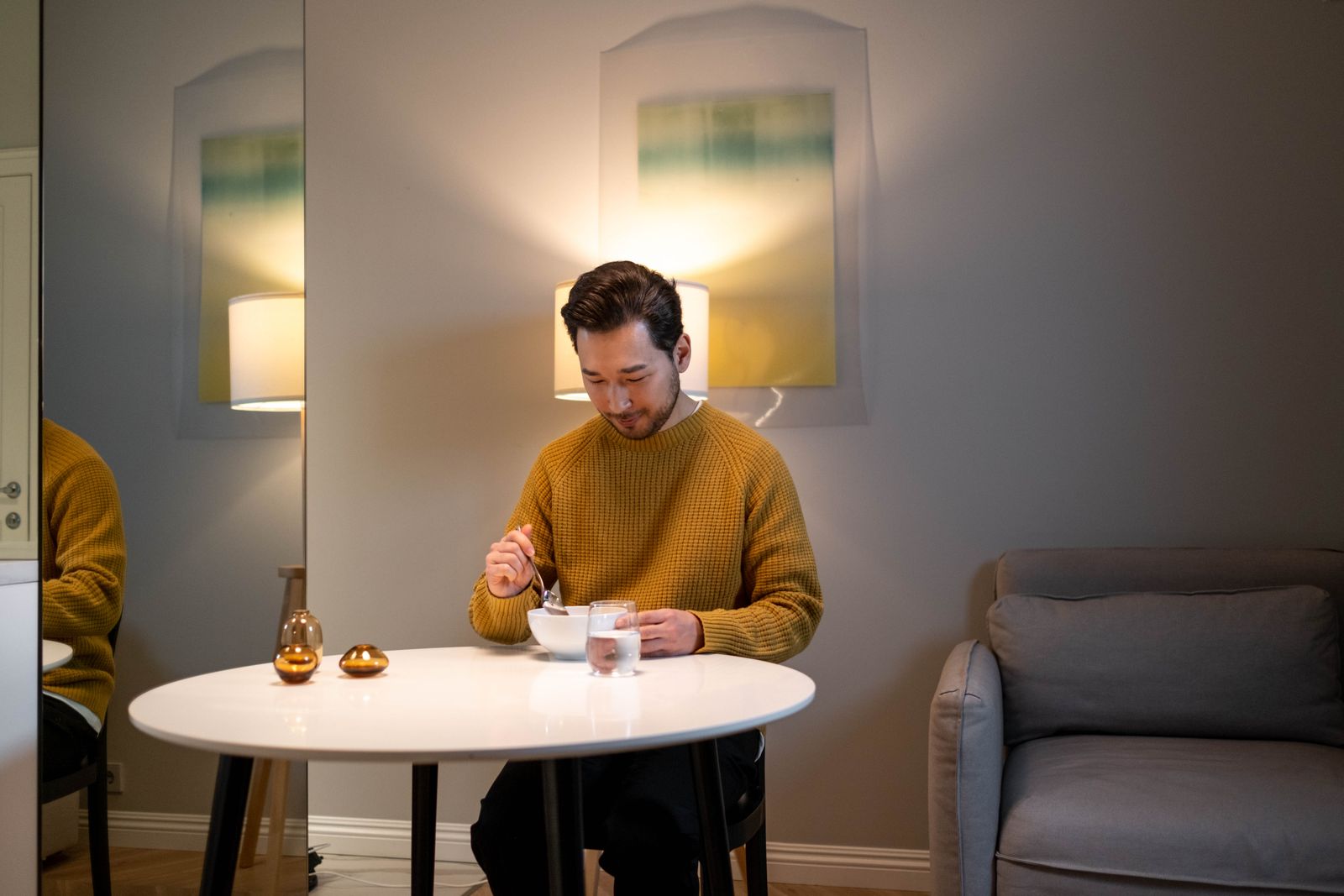 Man enjoying a meal at a cozy table with ambient lighting, creating a relaxed atmosphere.