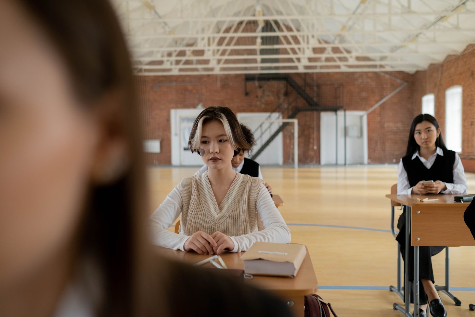 Students sitting at desks in a spacious, well-lit classroom, focusing attentively.