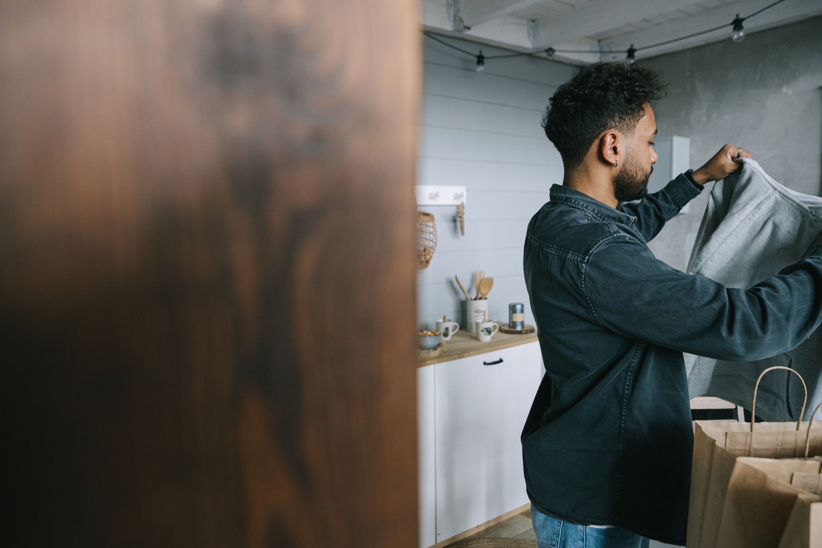 Adult man sorting clothes in a stylish kitchen environment, engaging in home organization.