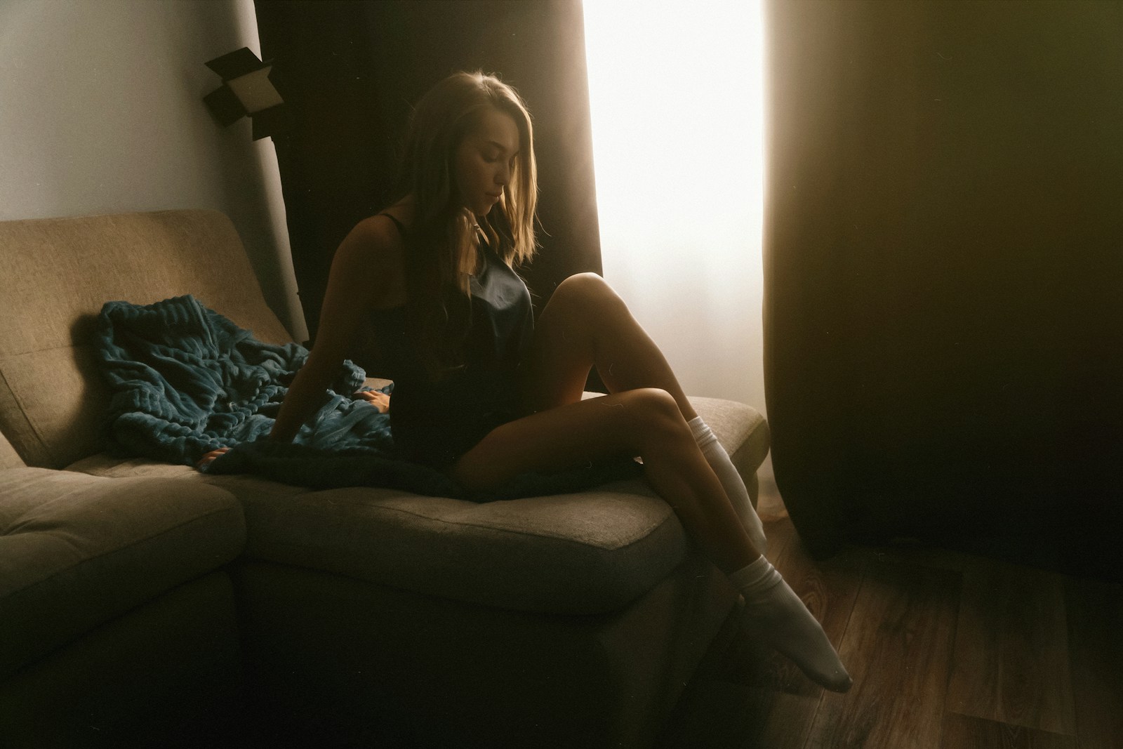A woman sitting on a couch in front of a window