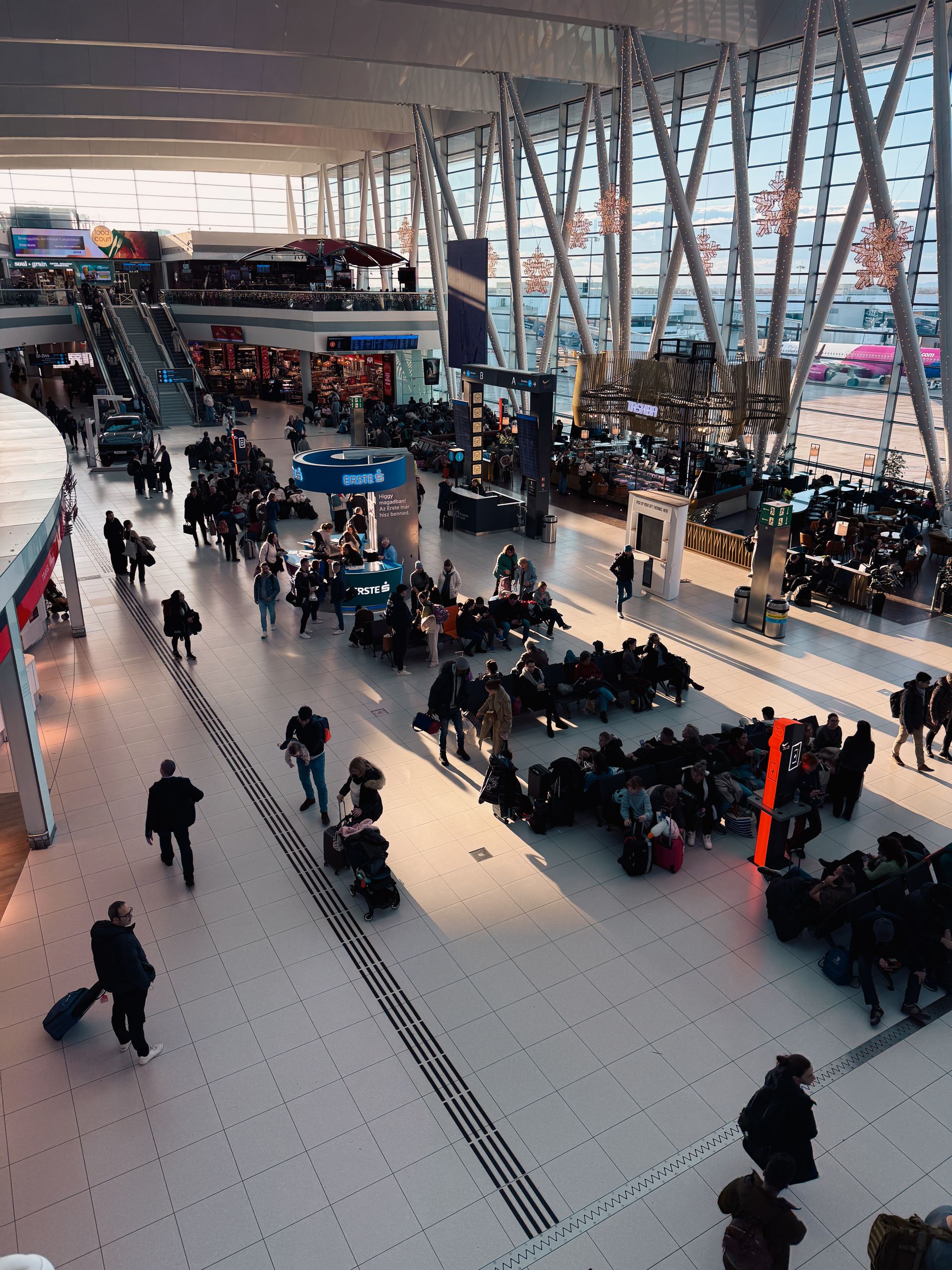 A bustling airport terminal with travelers waiting and moving through the space.
