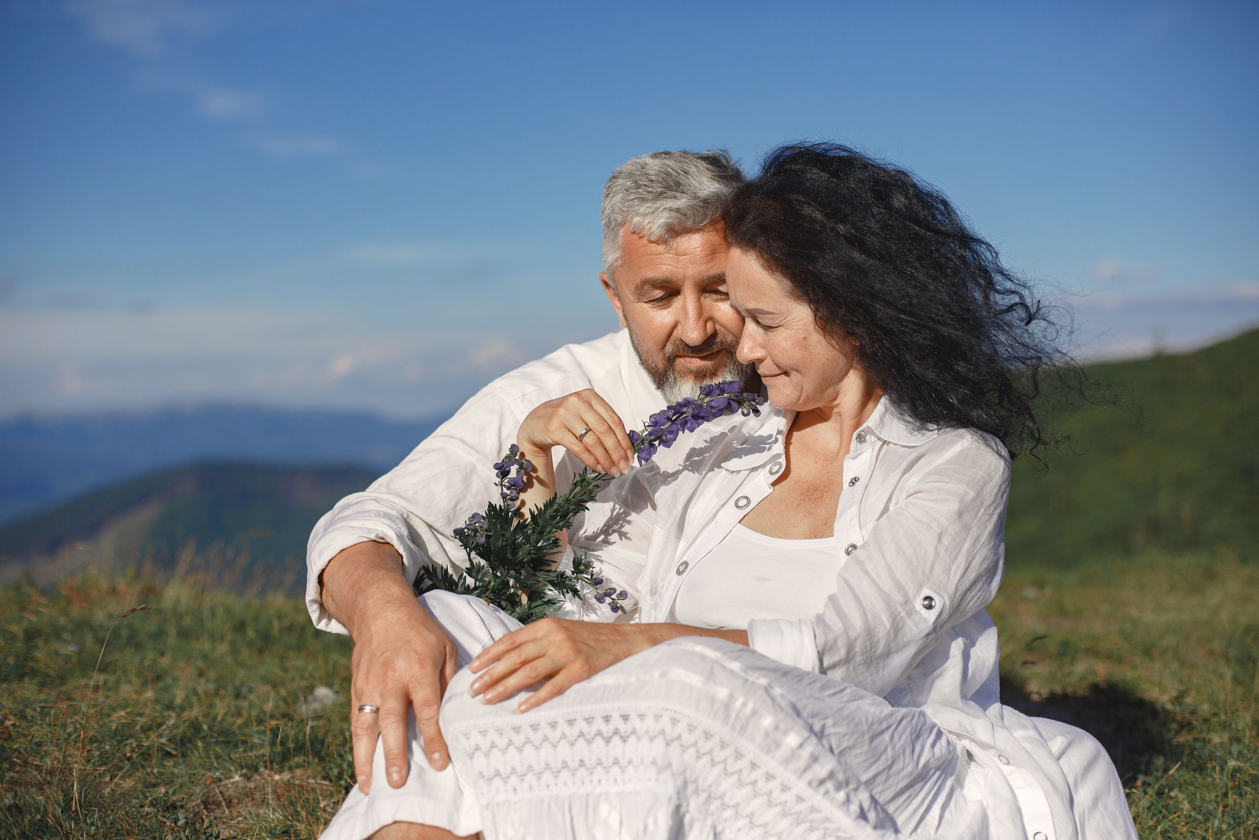 A loving couple embraces outdoors, enjoying nature and sunshine.