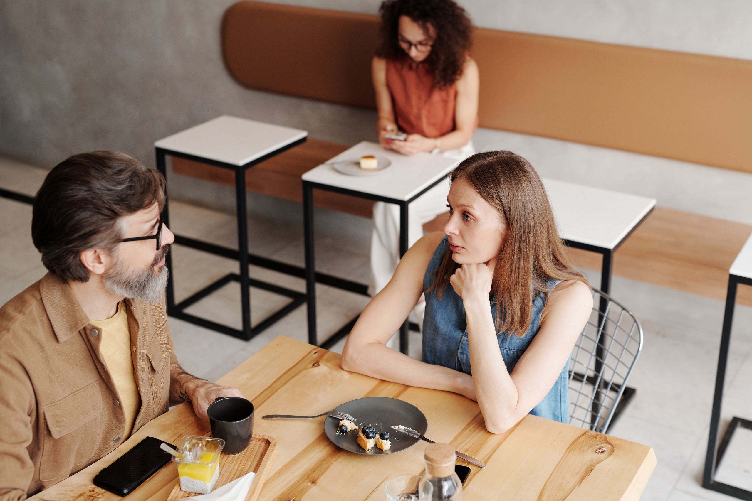 A man and woman engage in conversation over breakfast at a stylish coffee shop.