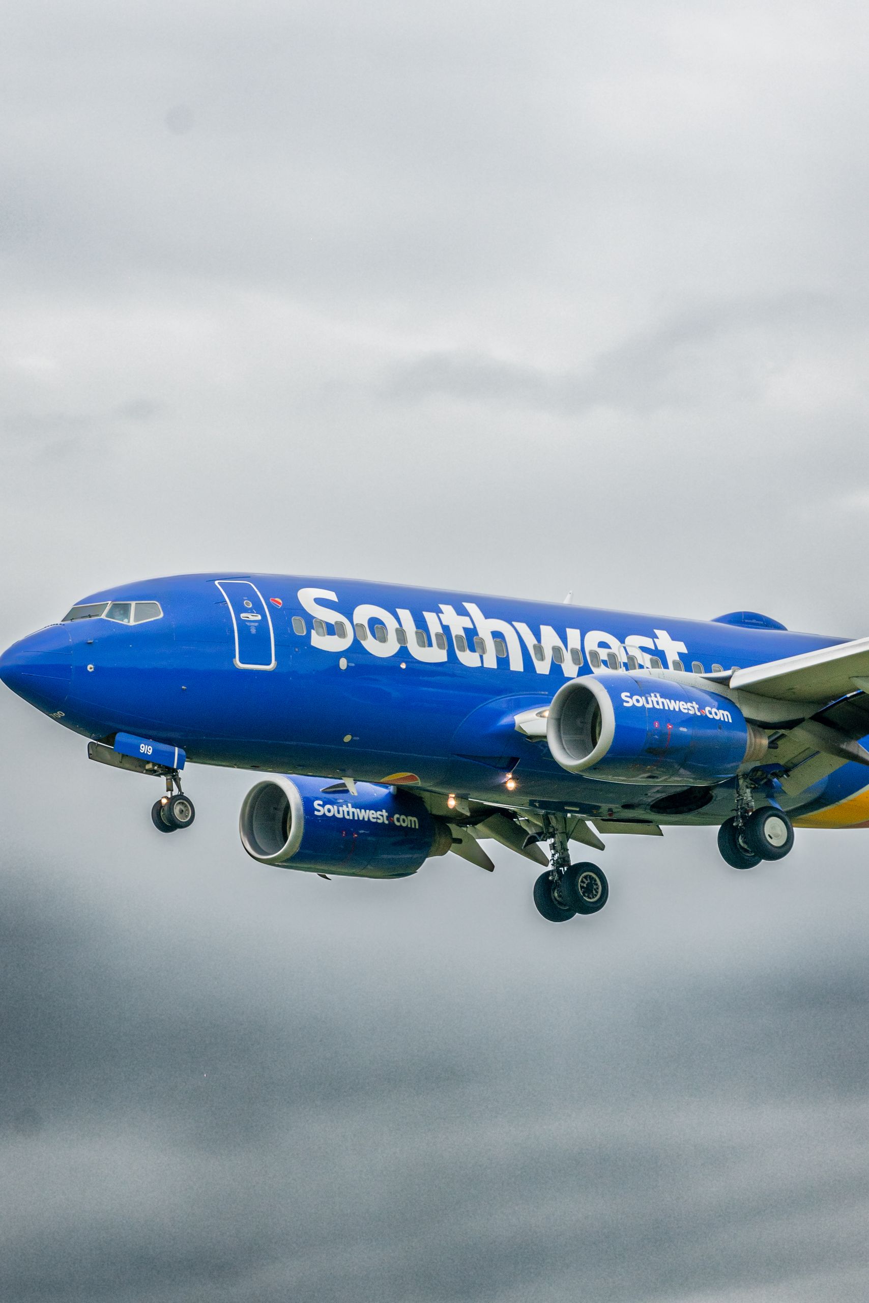 A Southwest Airlines airplane flying under a cloudy sky.
