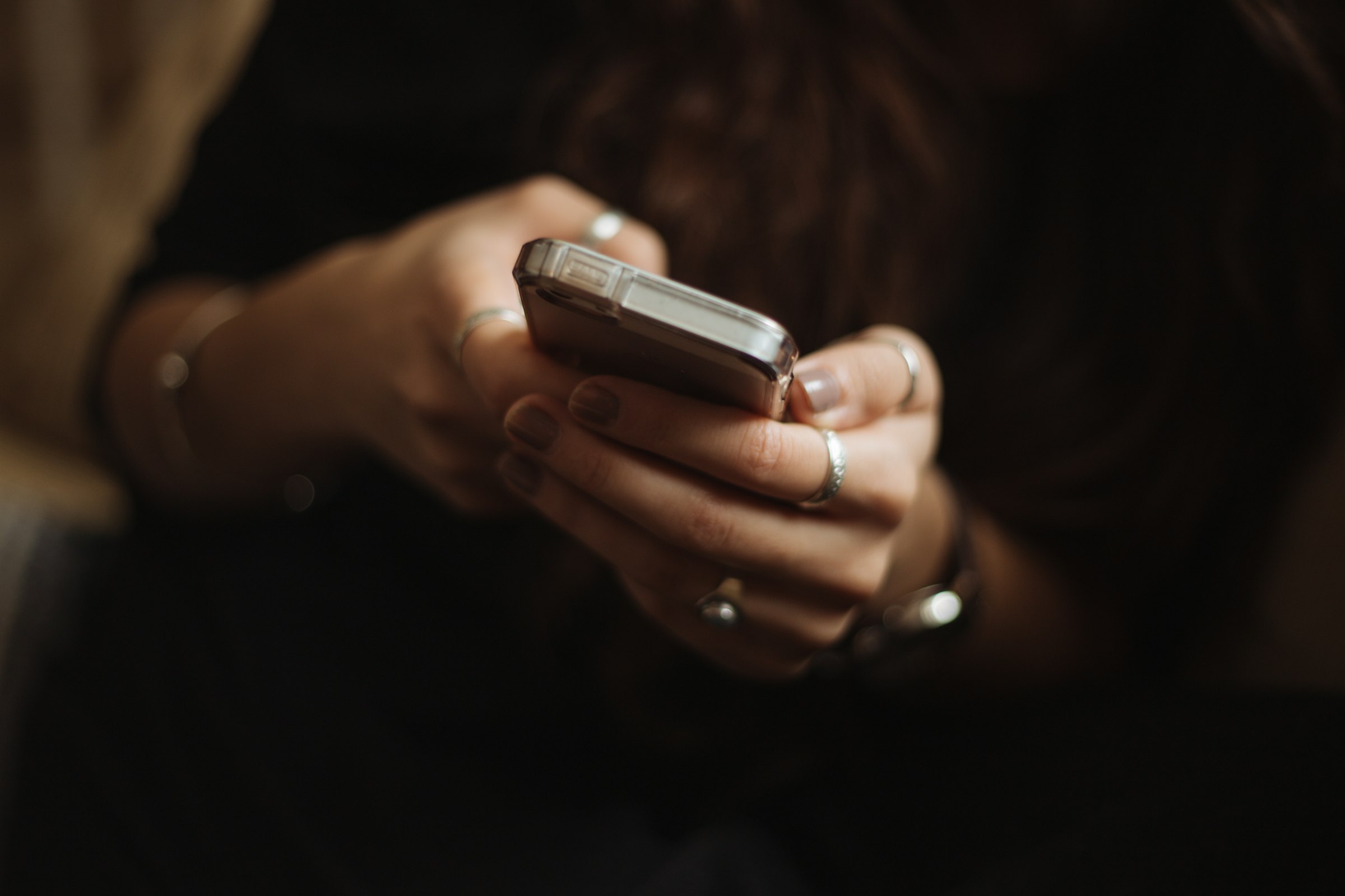 A woman holds a smartphone with soft natural light and a blurred background, representing singles using AI-powered dating apps