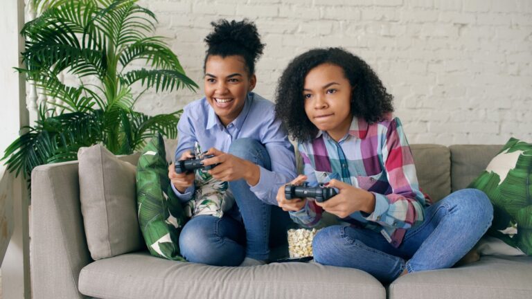 Two women playing video games on a couch