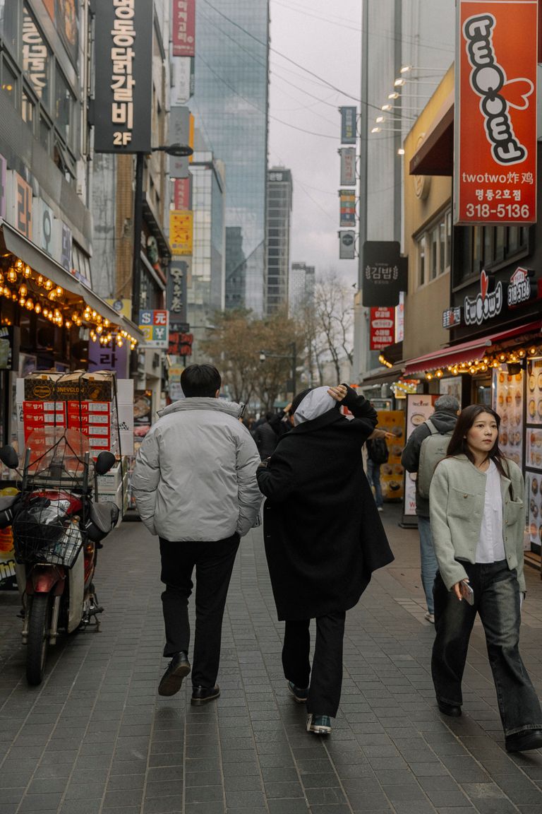 Bustling city street with pedestrians and colorful store signs, capturing urban life.