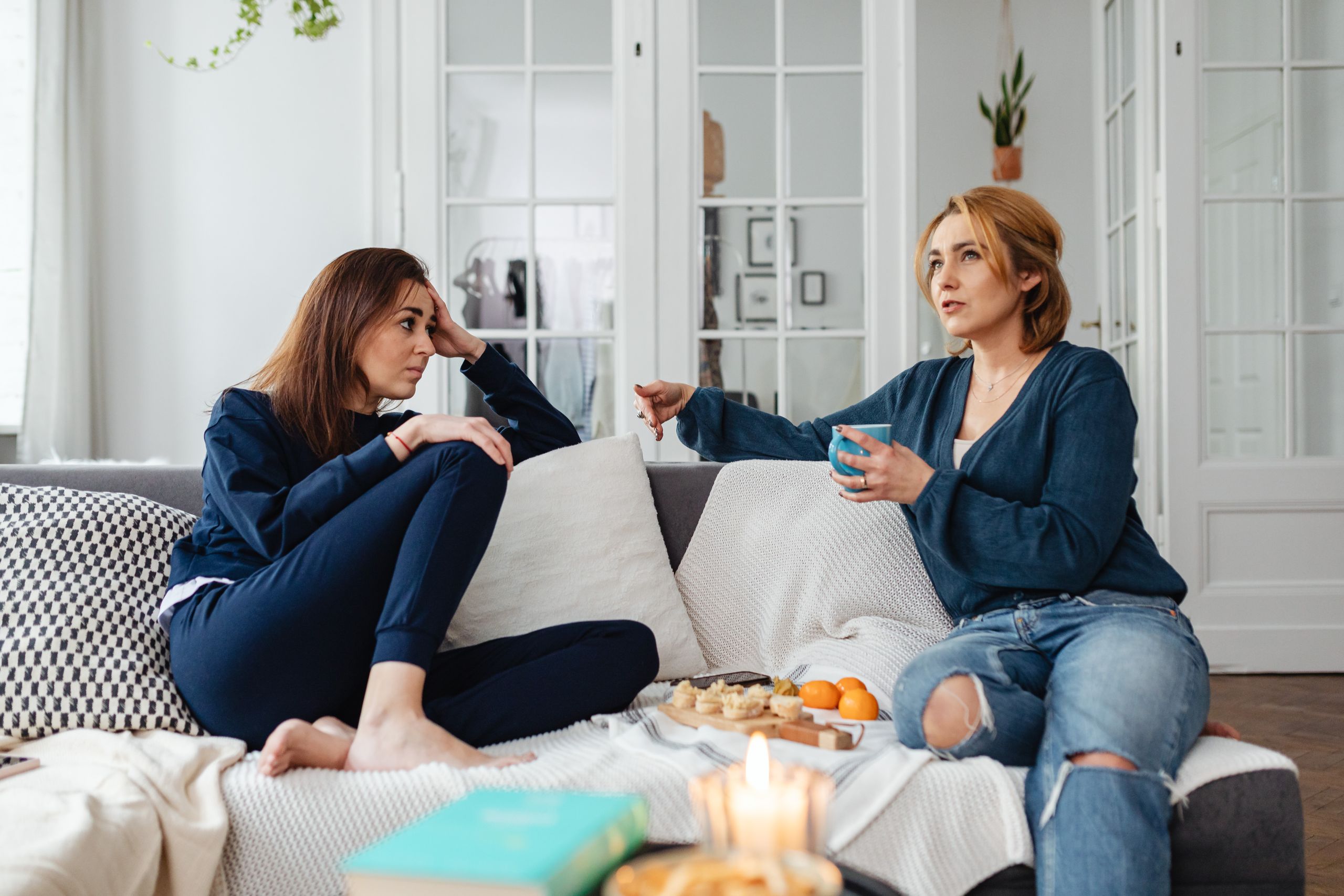 Casual conversation between two women indoors on a comfortable sofa.