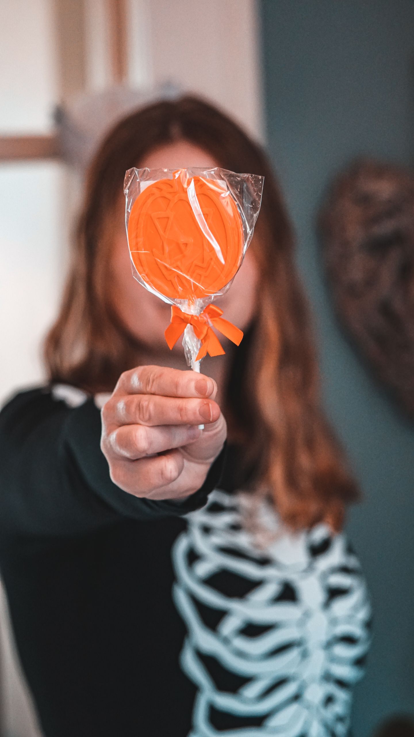 Close-up of a Halloween-themed lollipop held by a person in a skeleton costume, creating a festive atmosphere.