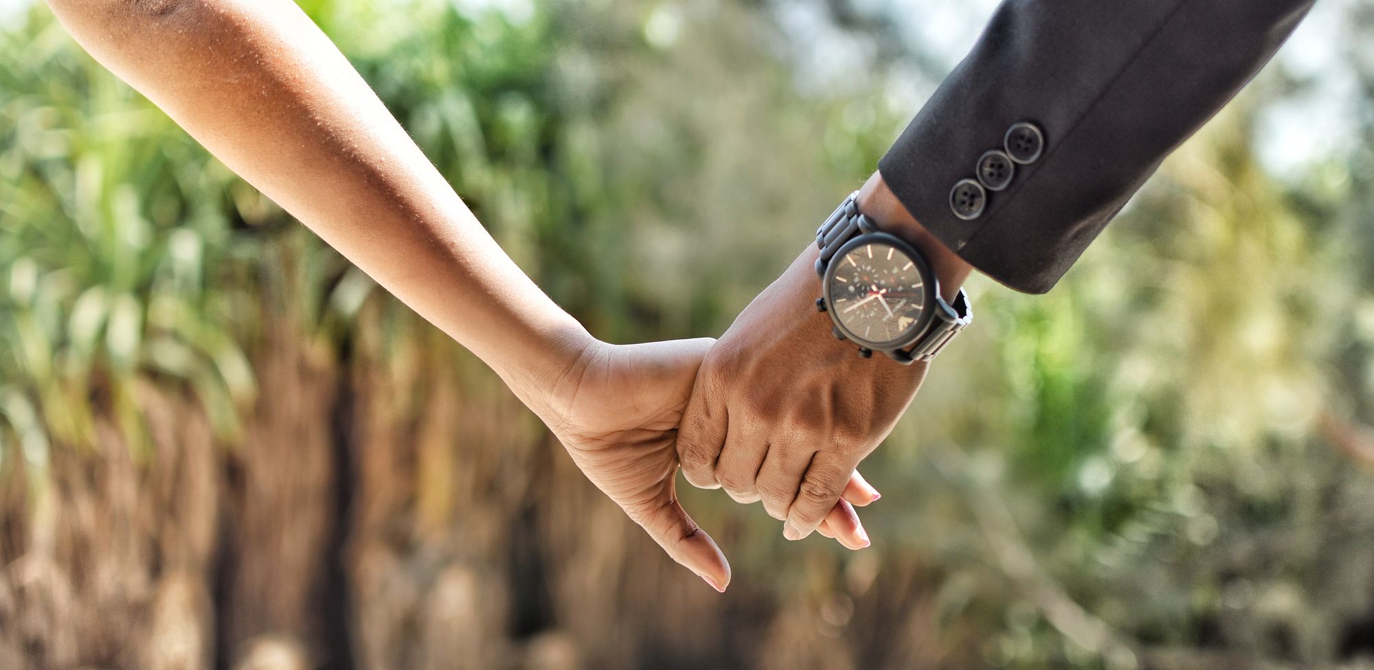 Close-up of a couple's hands intertwined outdoors in soft natural sunlight, symbolizing reconciliation and renewed connection