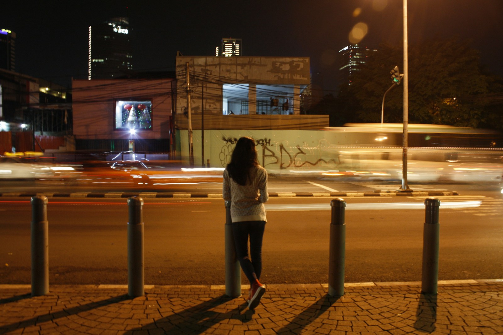 Woman standing alone on a street at night.