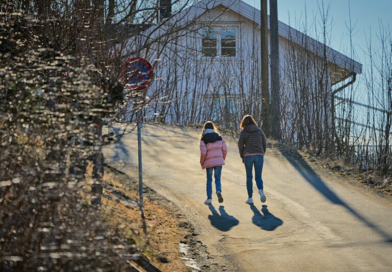a couple of women walking down a dirt road