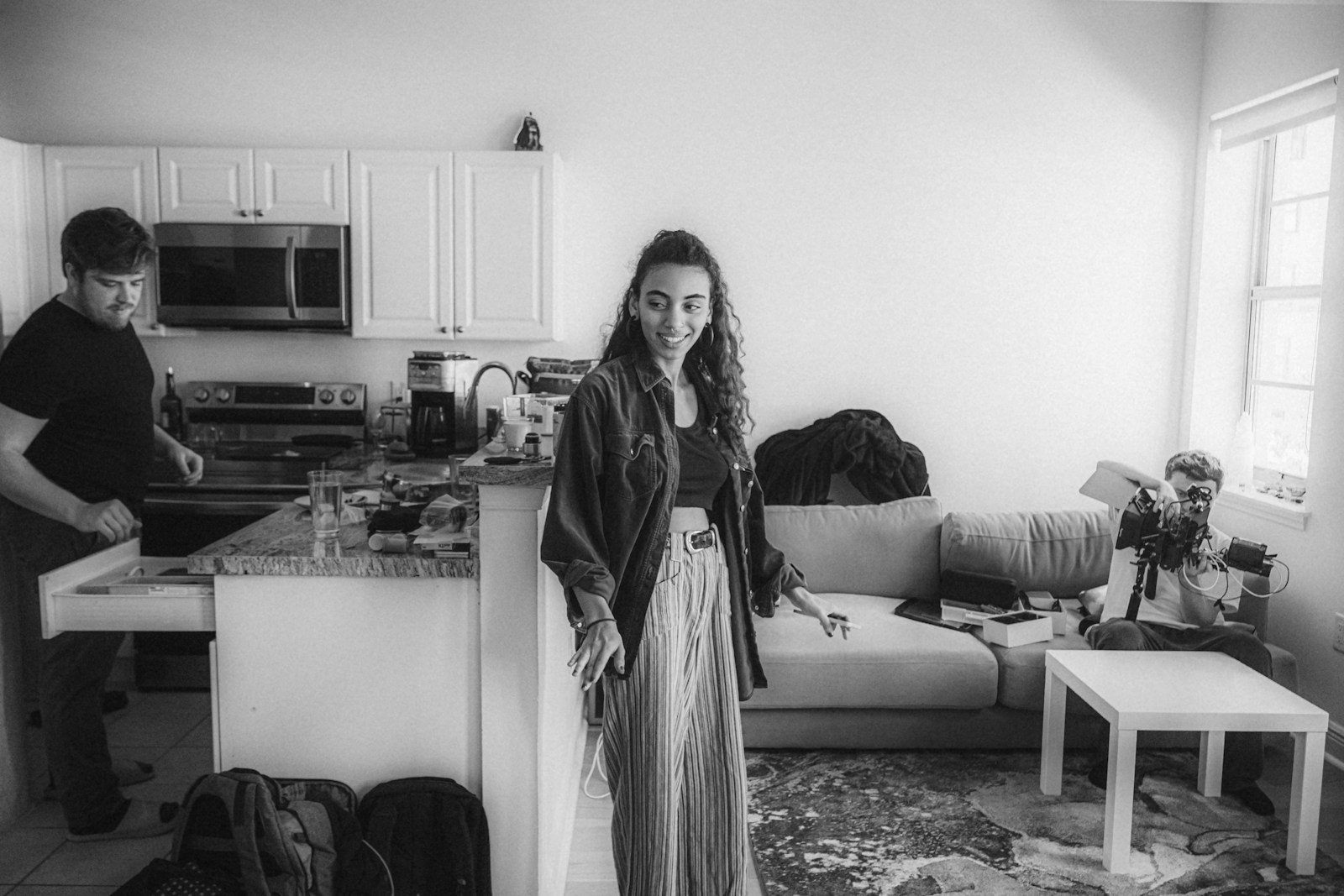 a black and white photo of a woman standing in a kitchen