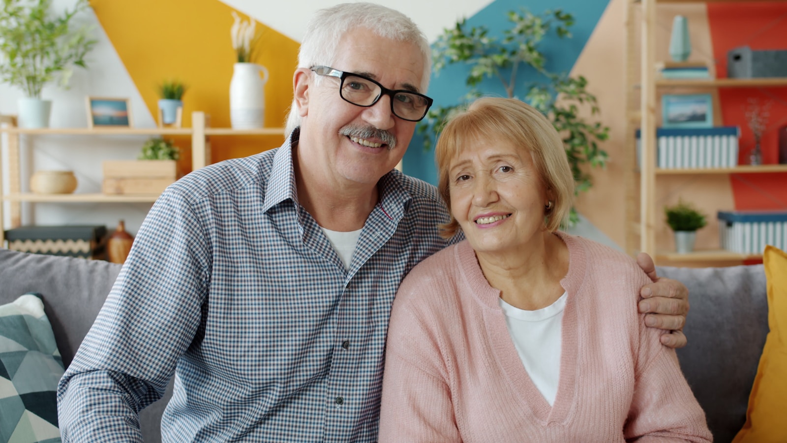 Elderly couple smiling together on a couch