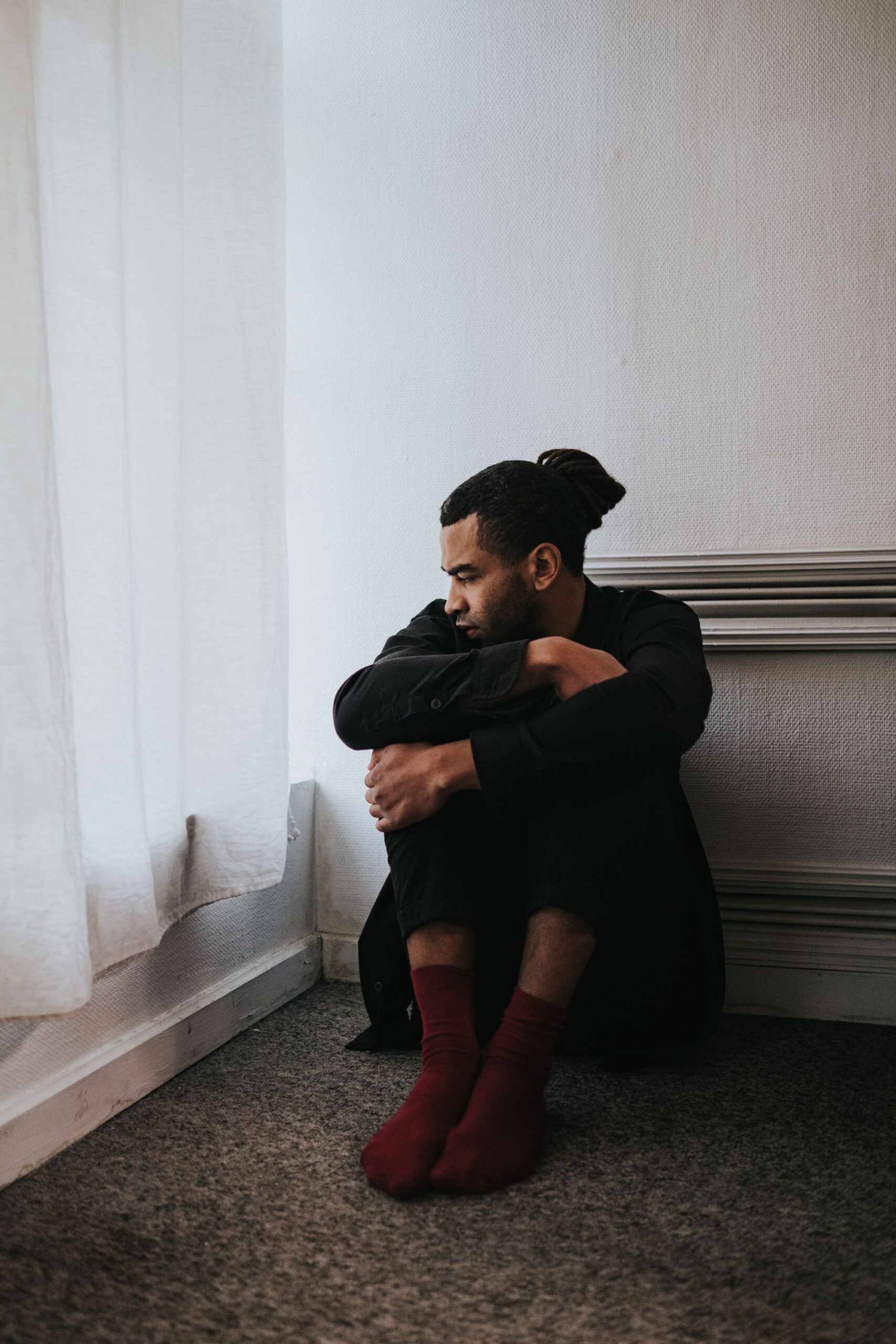 An older man sitting alone by a window in quiet, contemplative light