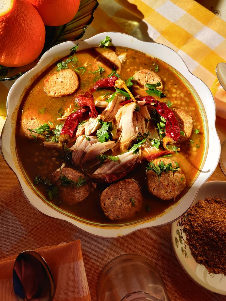 Hearty pozole rojo with chicken, sausage, and chiles garnished with cilantro.