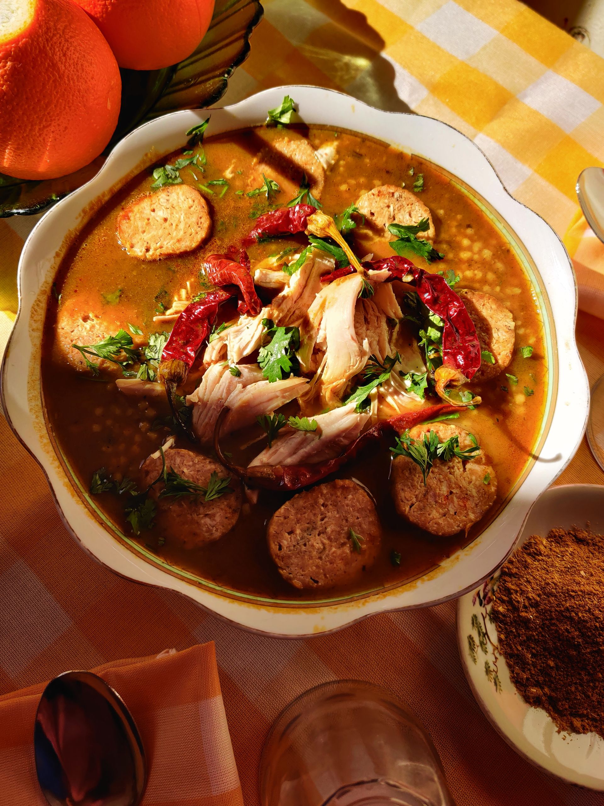 Hearty pozole rojo with chicken, sausage, and chiles garnished with cilantro.