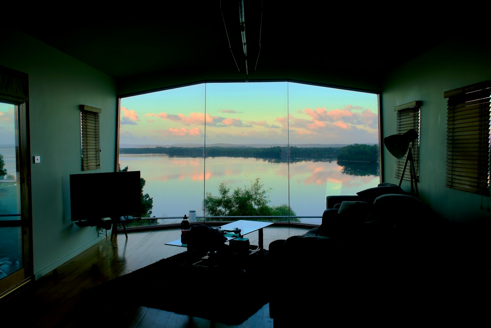 Living room with large window overlooking lake at sunset