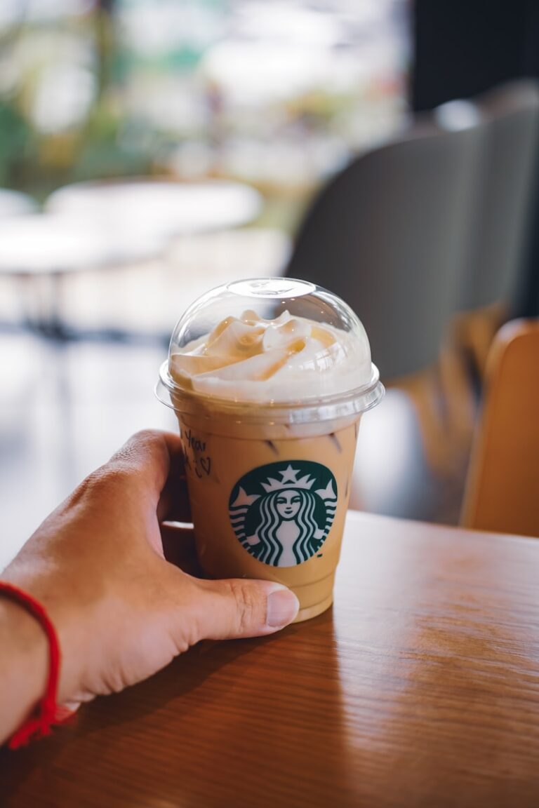 Hand holding a starbucks iced coffee with whipped cream