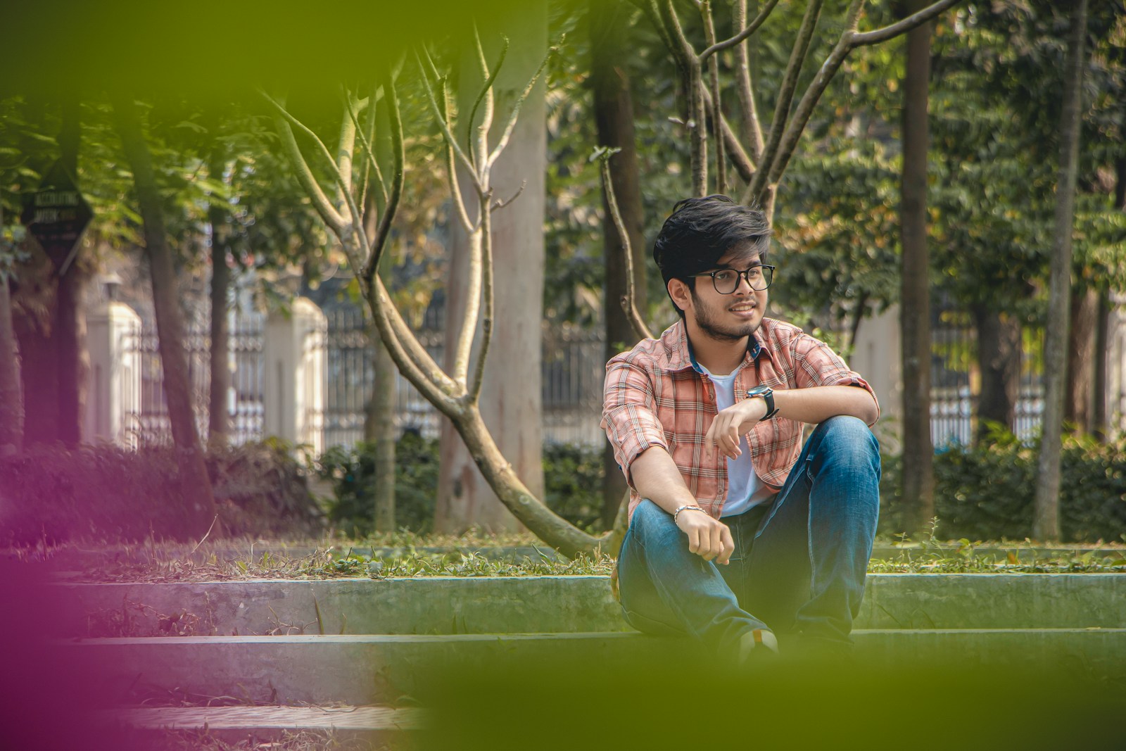 a man sitting on the ground next to a tree