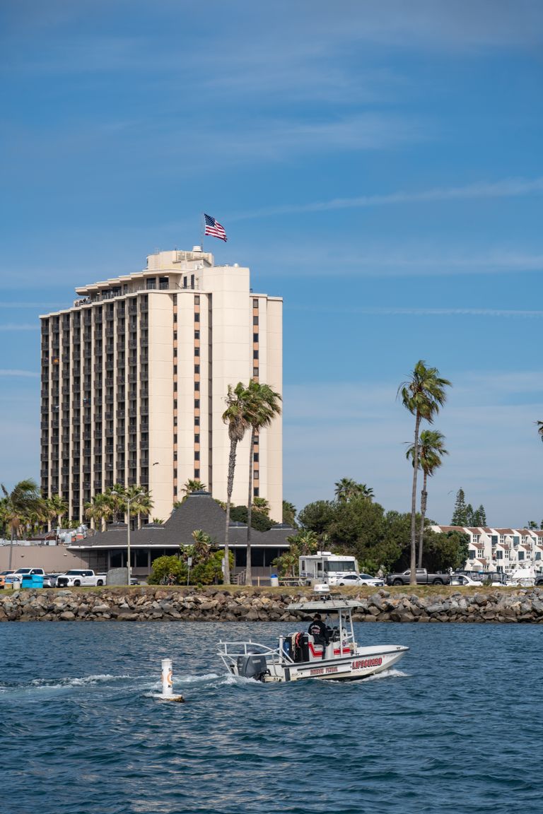 Lifeguard boat patrolling Mission Bay with a hotel and palm trees in San Diego.
