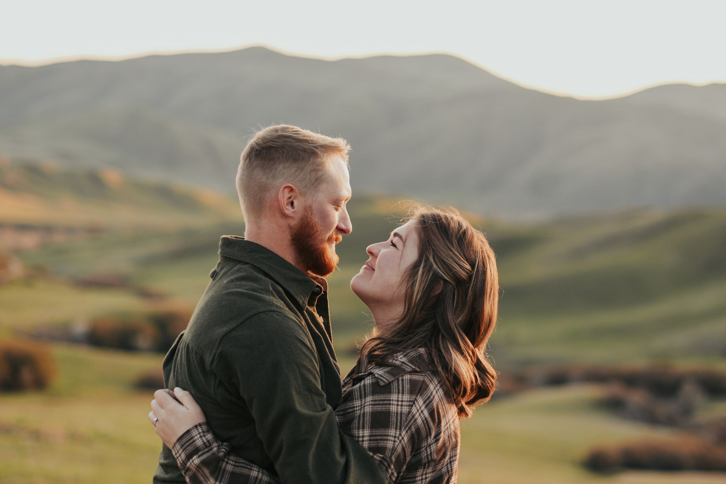 A couple embracing and gazing into each other's eyes outdoors at golden hour