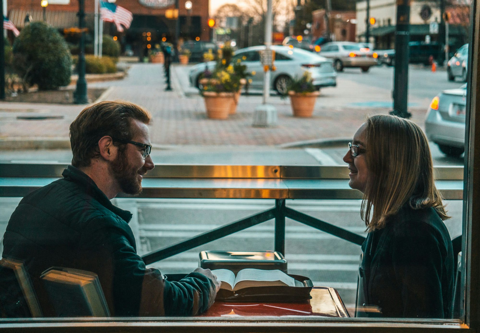 A couple sitting outdoors in daylight, engaged in an open, honest conversation