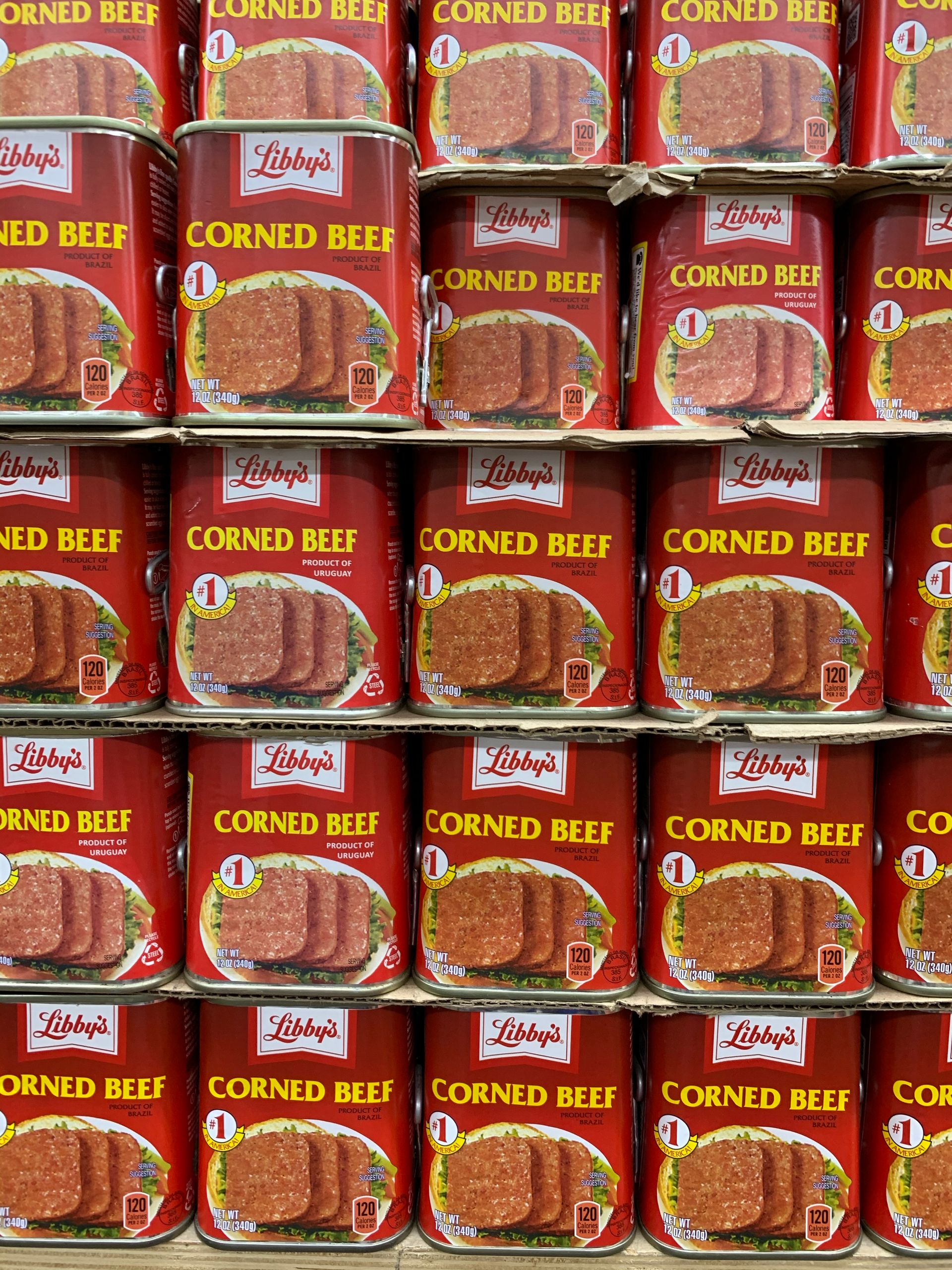 Multiple cans of corned beef neatly organized on supermarket shelves.
