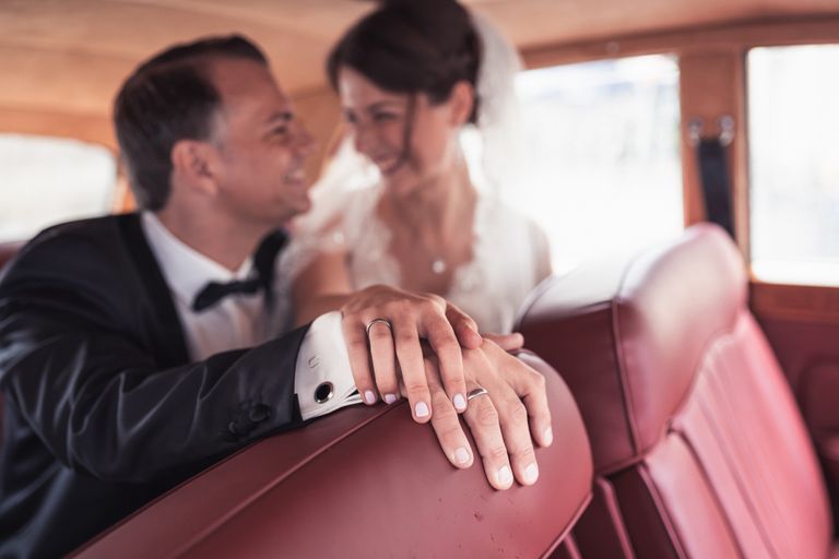 Newlyweds sharing a tender moment inside a vintage car on their wedding day.