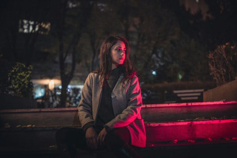 A woman sitting on a bench at night