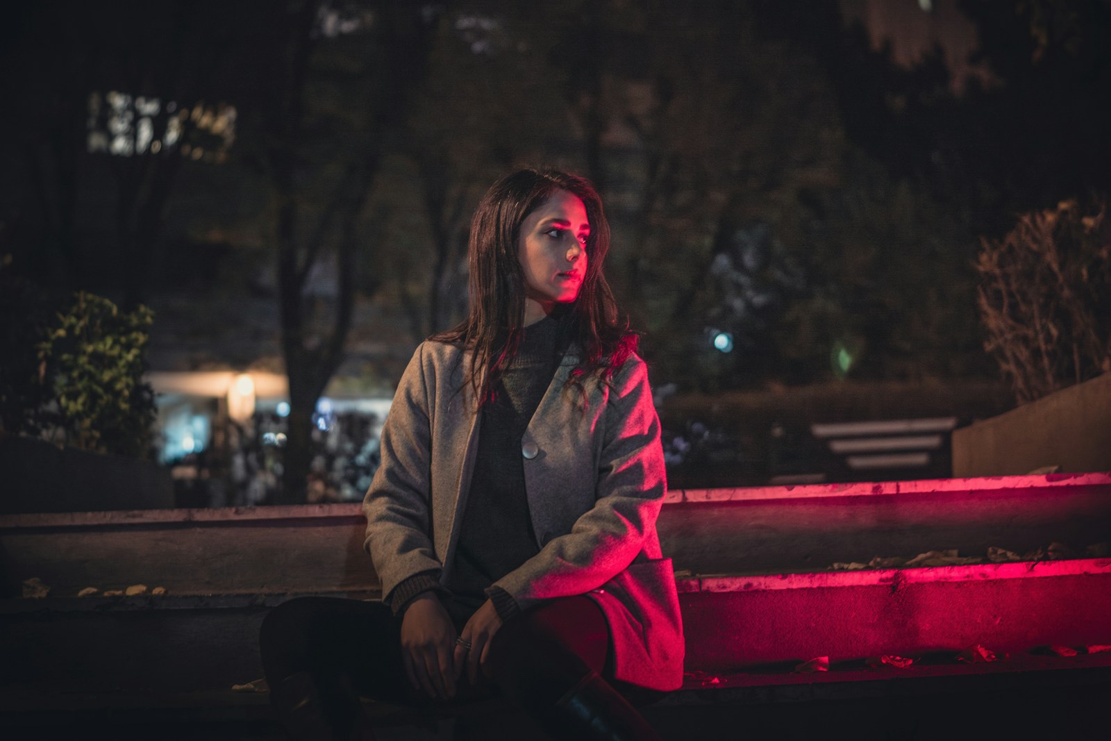 A woman sitting on a bench at night