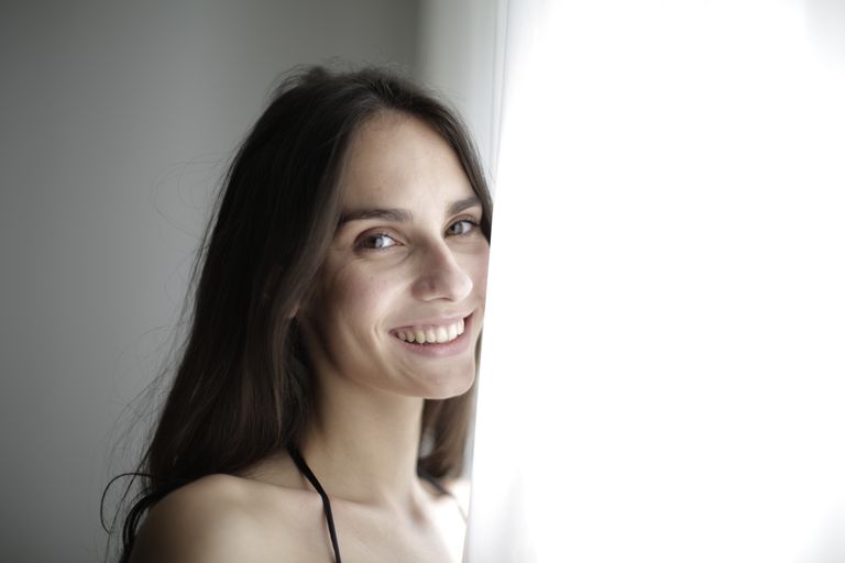 Portrait of a smiling woman with brunette hair in soft natural light, exuding happiness and warmth.