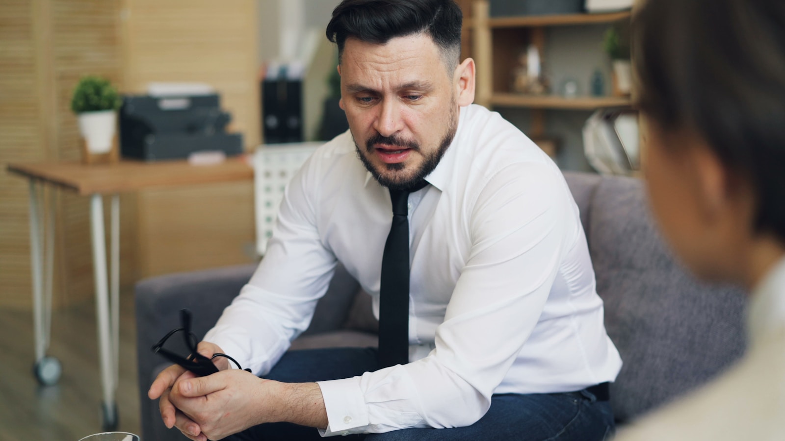 a man in a white shirt and tie sitting on a couch