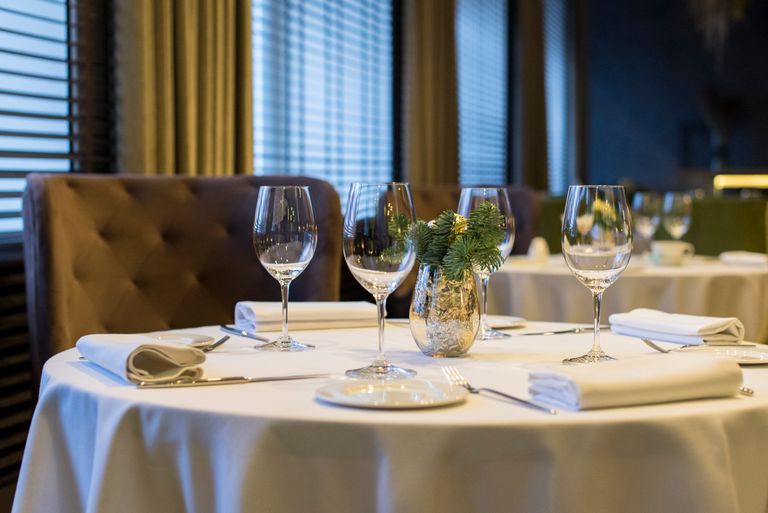 Sophisticated dining setup with polished wine glasses, white napkins, and a decorative centerpiece on a round table.
