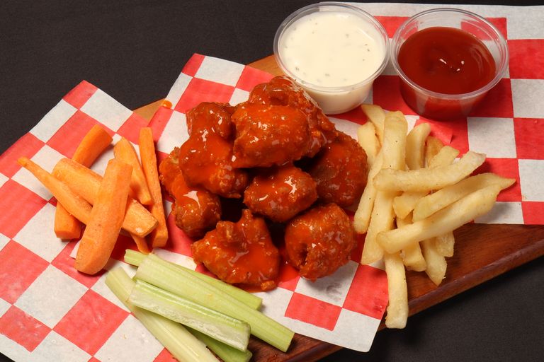 Tasty buffalo wings with vegetables and fries, perfect for a snack or party platter.