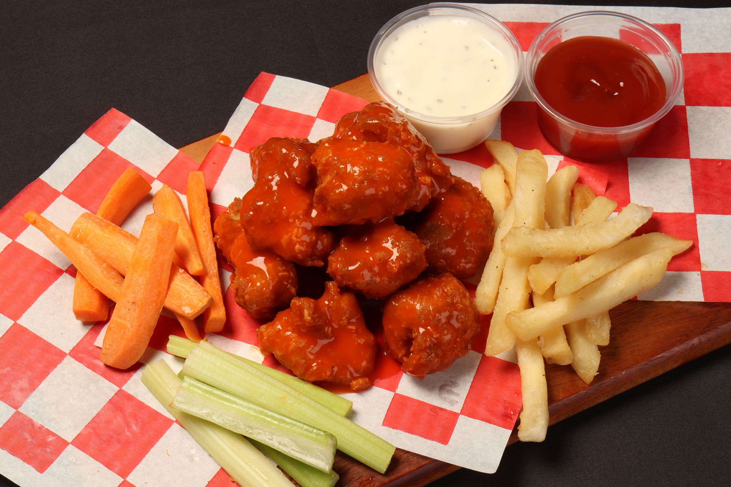 Tasty buffalo wings with vegetables and fries, perfect for a snack or party platter.