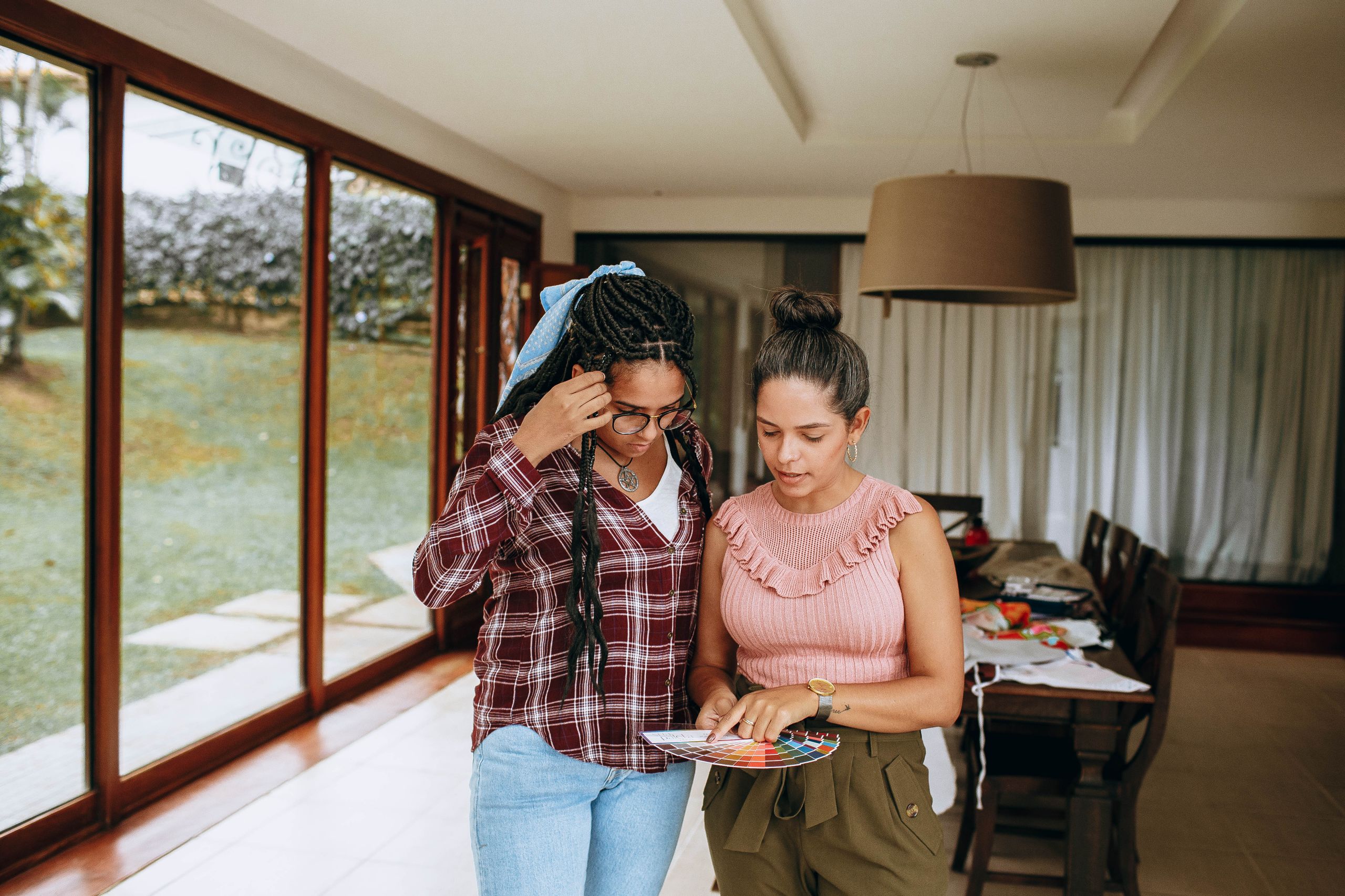 Two women reviewing color swatches in a bright living room, focusing on design options.