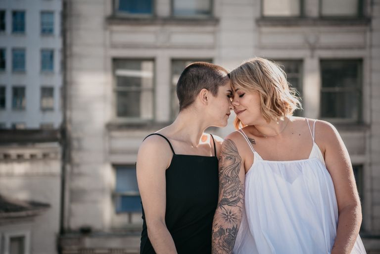 Two women share an intimate moment in an urban setting, symbolizing love and togetherness.