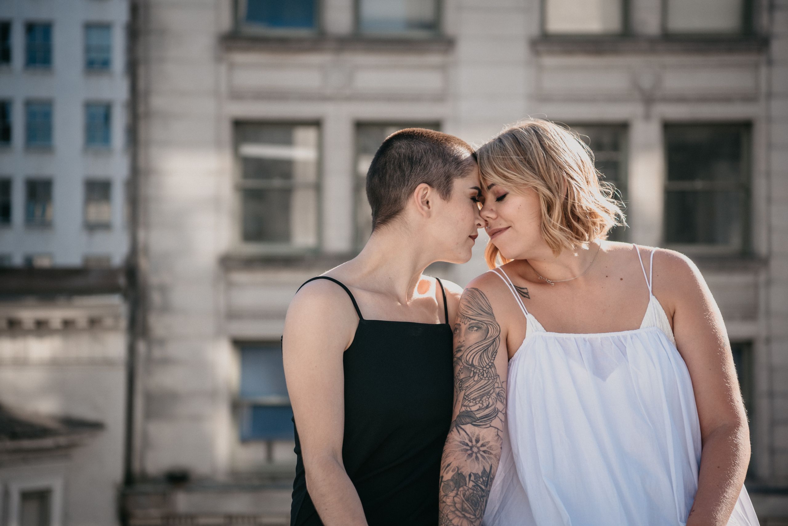Two women share an intimate moment in an urban setting, symbolizing love and togetherness.